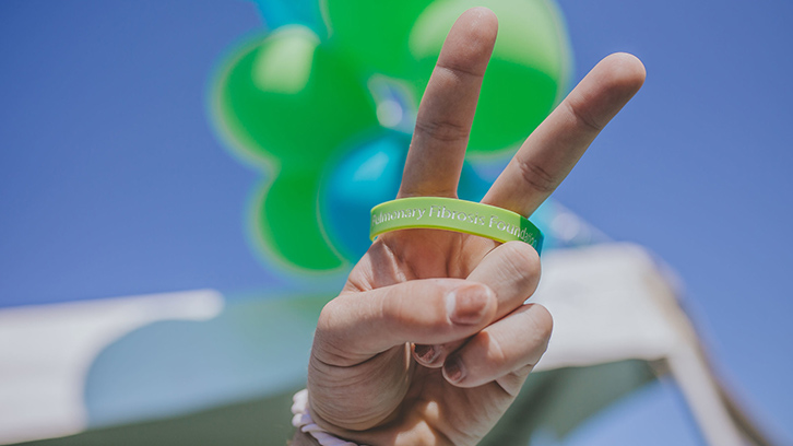 Hand with a peace sign in front of balloons